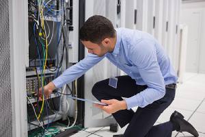 A managed IT services professional checking plugin cables into server in data center