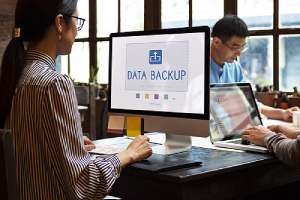 woman sitting at her computer with the words data backup on her screen showing a cloud network data backup concept