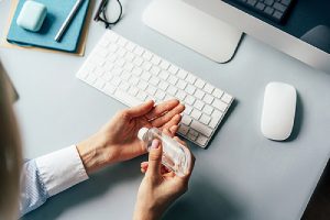 A remote office setup and a person treats hands with a disinfectant
