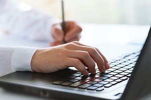 man typing on his laptop and speaking to an IT consultant in Alexandria va