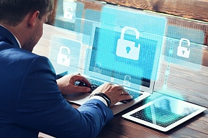 man working on his laptop with it security symbols on the screen