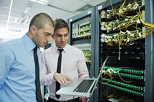 two IT experts standing in a server room trying to resolve a problem