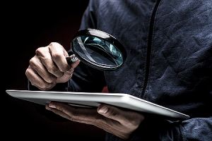 Man holding a magnifier depicting cyber security threat. A network security assessment is a must for every business