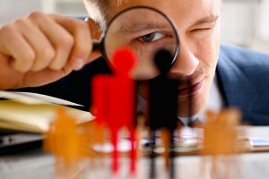 man in suit look thru loupe on statuettes closeup in office