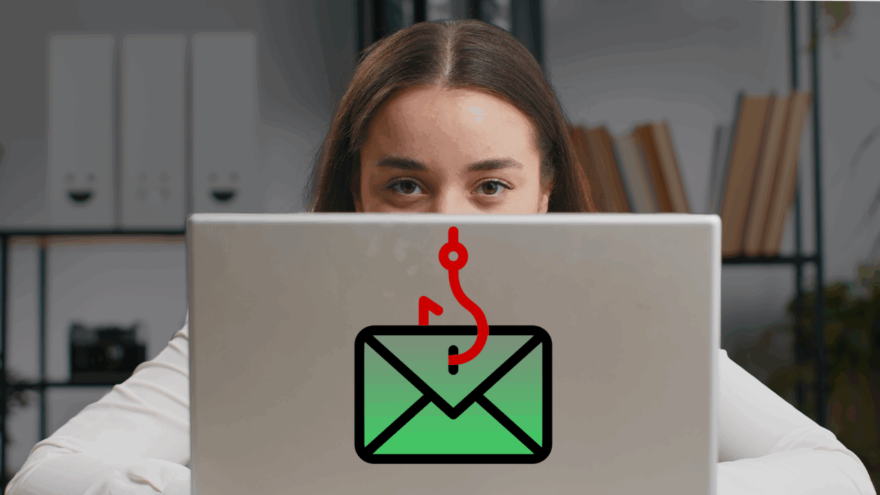 An overconfident team member looking at the camera behind a laptop with a phishing symbol